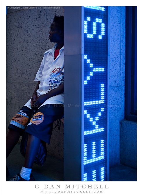 Person Sitting Behind Blue Sign, 7th Avenue Person Sitting Behind Blue Sign, 7th Avenue
